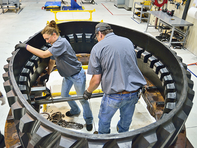 When used tracks arrive outside the Camso facility, inspectors make sure the core is structurally sound and suitable for remanufacturing. Workers apply an adhesive to bond new guide bars and tread bars to the carcass, Image by Jim Patrico